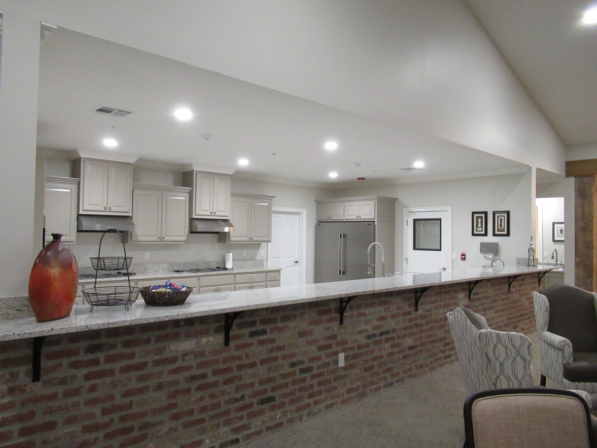 A modern kitchen with brick accent and counter seating, featuring recessed lighting.