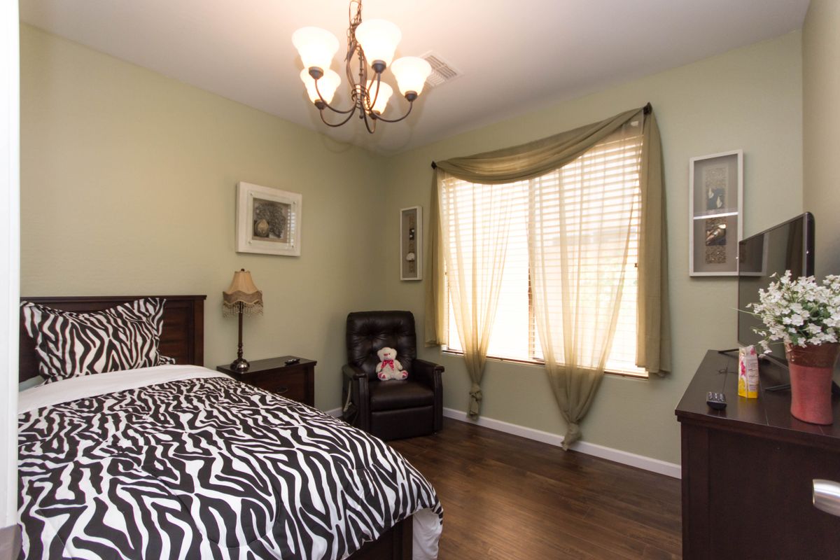 A cozy bedroom with zebra-patterned bedding, a black chair, and a chandelier.