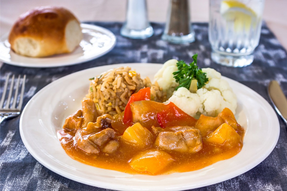 A plated meal featuring chicken stew with vegetables, rice, and cauliflower.