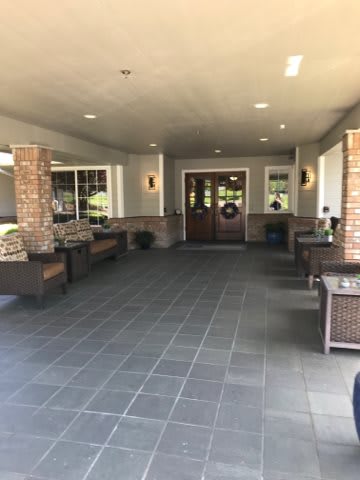 A covered entrance with outdoor seating leading to a building's main door.