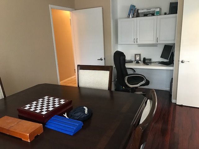 A home office setup featuring a desk with a computer and a table with a chessboard.