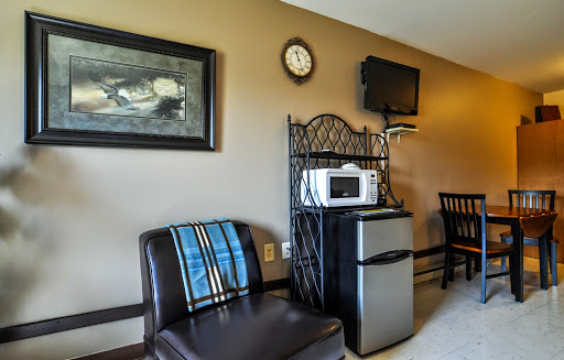 A cozy hotel room corner featuring a comfortable chair, a mini refrigerator, microwave, and a television.