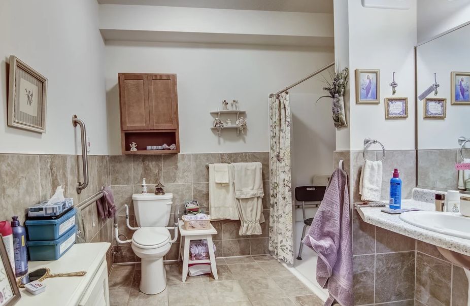 A neatly arranged bathroom featuring a toilet, shower with curtain, and various towels and decor.