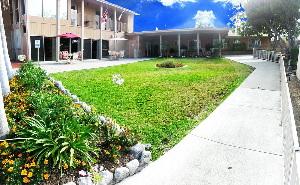 A sunny day view of a building with a well-maintained lawn and garden.