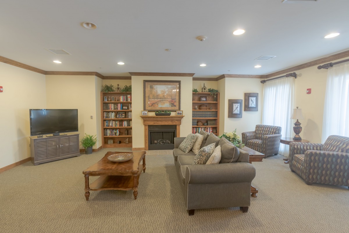 A cozy living room with a sofa, coffee table, and fireplace surrounded by bookshelves.