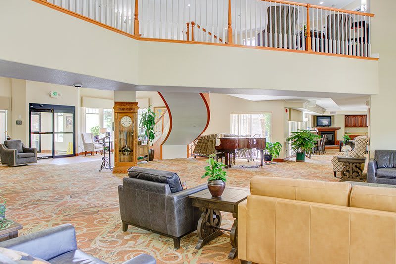 A spacious lounge area with elegant furniture, a piano, and a spiral staircase.