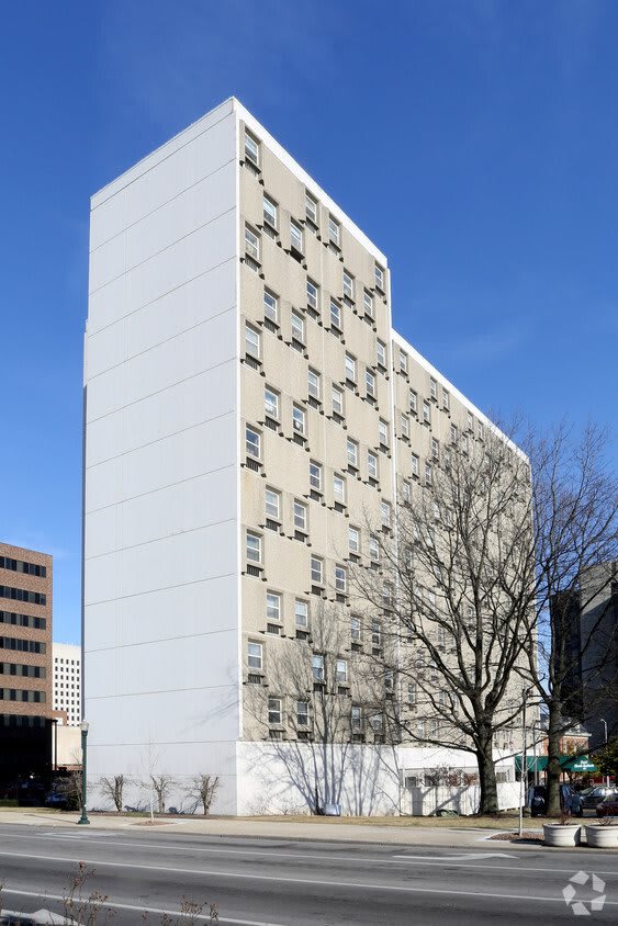 A modern high-rise building with a unique facade design against a clear blue sky.