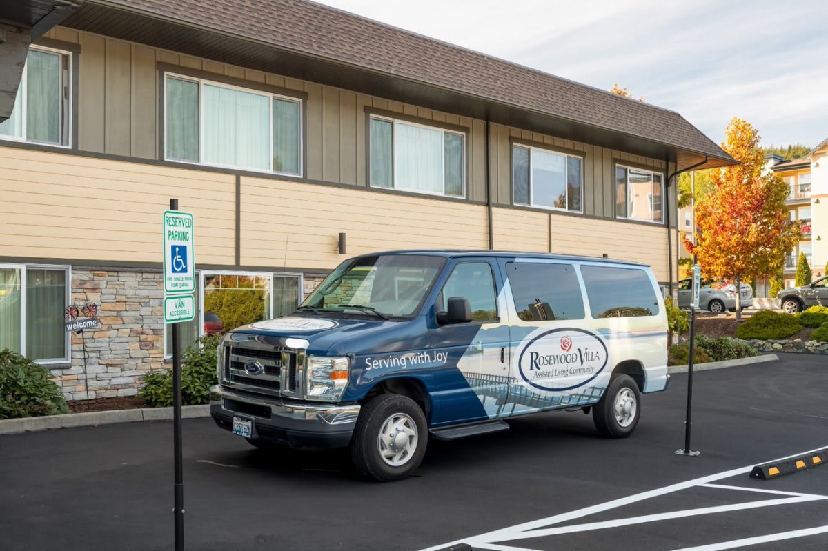 A van parked in a lot with handicap parking spaces near a building.