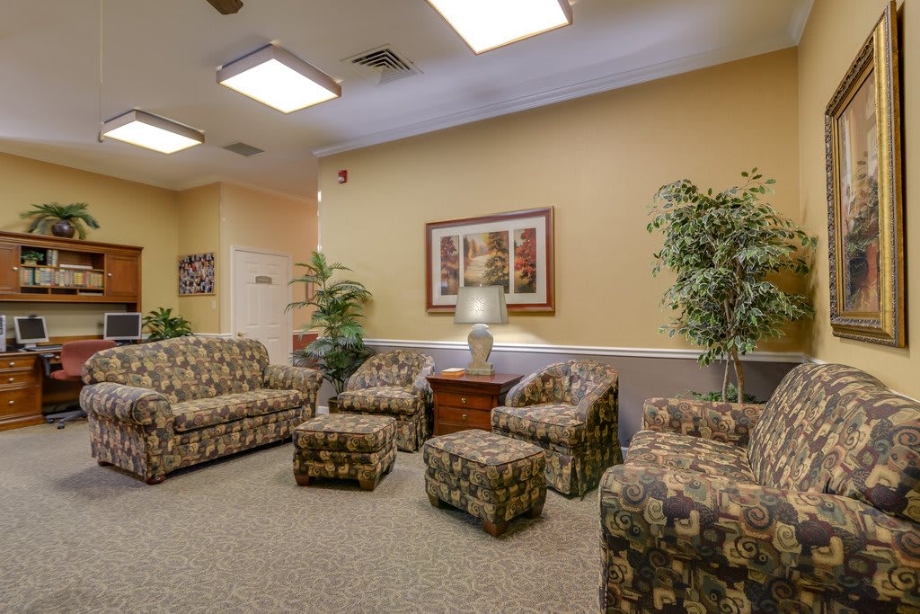 A cozy waiting room with patterned sofas, chairs, and decorative plants.