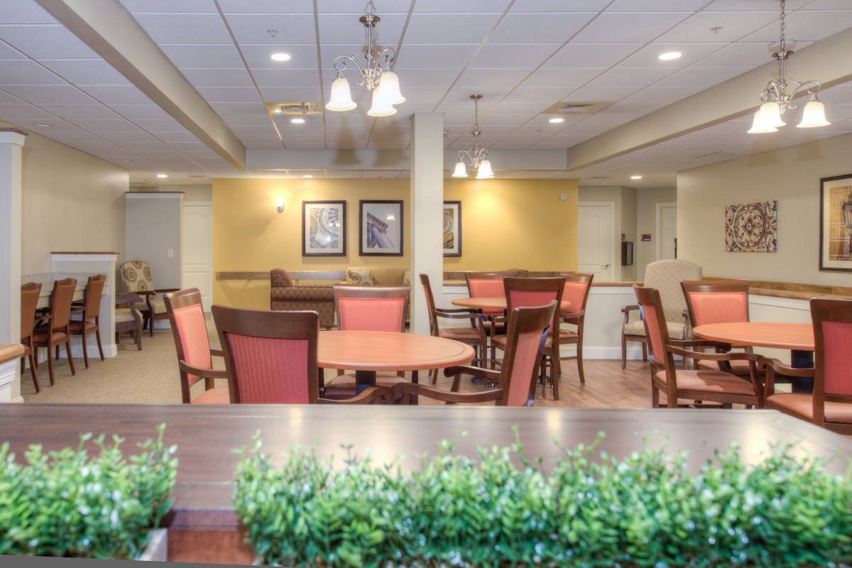 A cozy dining area with neatly arranged tables and chairs, softly lit by overhead lights.
