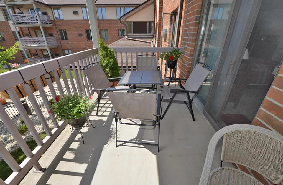 A sunny balcony with outdoor furniture and potted plants.