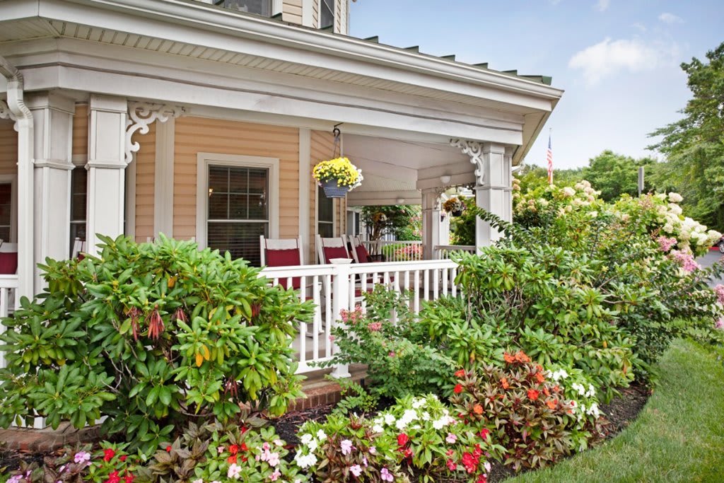 A charming front porch adorned with vibrant flowers and comfortable rocking chairs, creating a welcoming atmosphere.