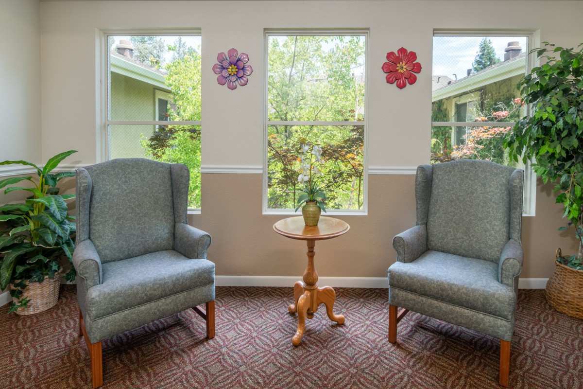 A cozy living room setup with two armchairs and a small table by the windows.