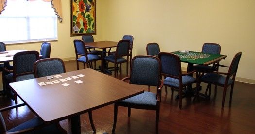 A room with multiple tables and chairs, featuring a colorful painting on the wall.