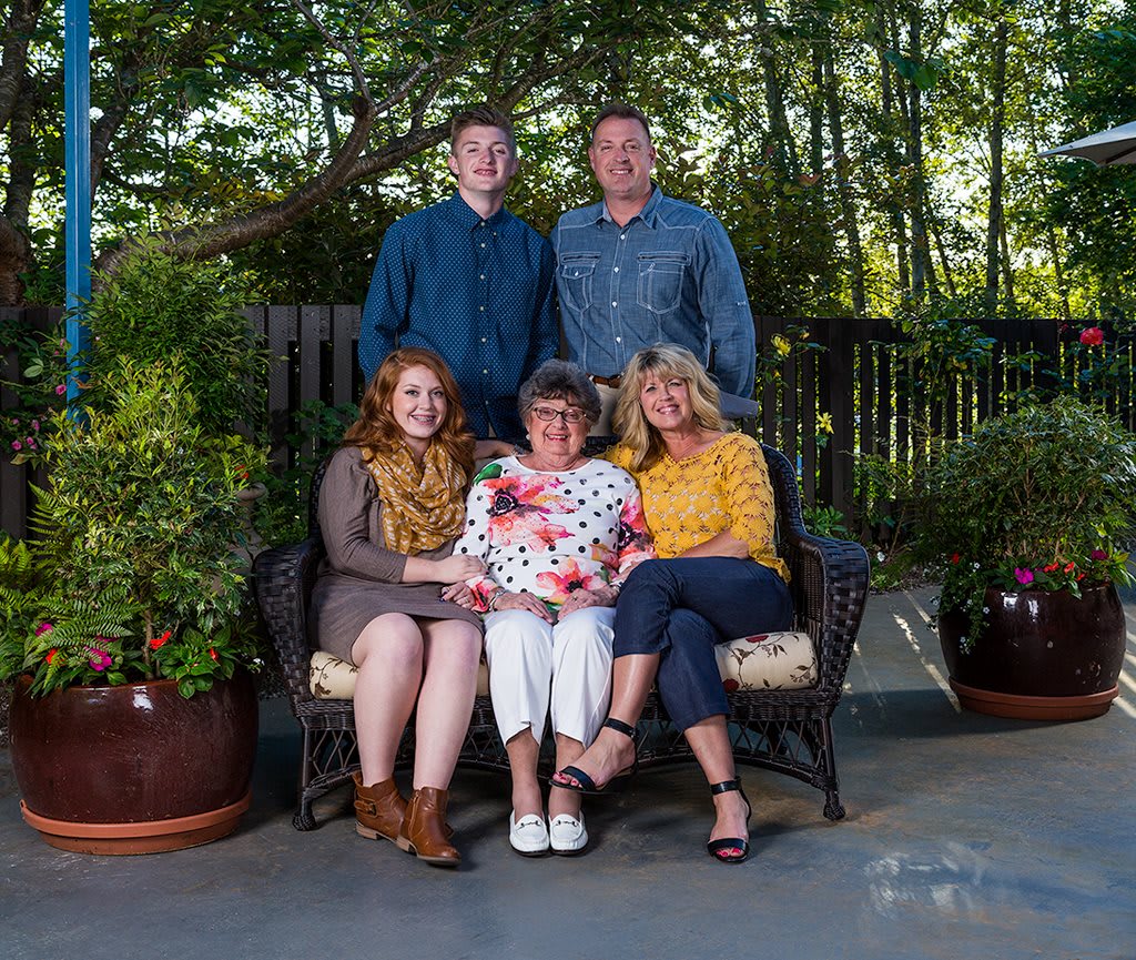 A family group portrait taken outdoors in a garden setting.