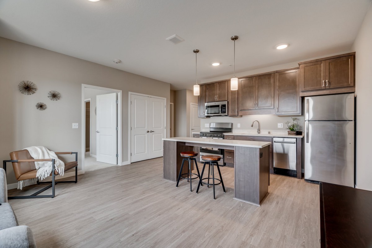 A modern kitchen with an open floor plan featuring a central island and stainless steel appliances.