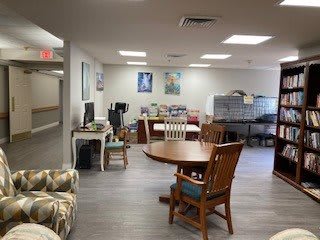 A cozy interior space featuring a round table, chairs, and a computer station.