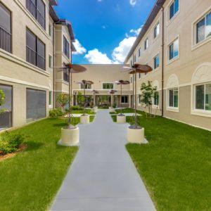 A view of a modern courtyard with a pathway and well-maintained landscaping.