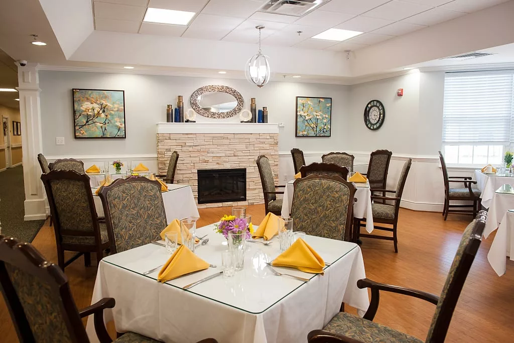 An elegantly set dining room with neatly arranged tables and a cozy fireplace.