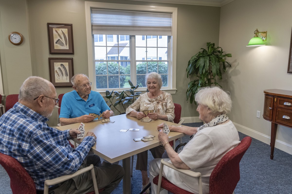 A group of seniors enjoying a card game together at a table indoors.
