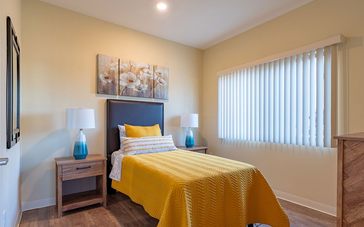 A modern bedroom with a single bed featuring yellow bedding and stylish decor.