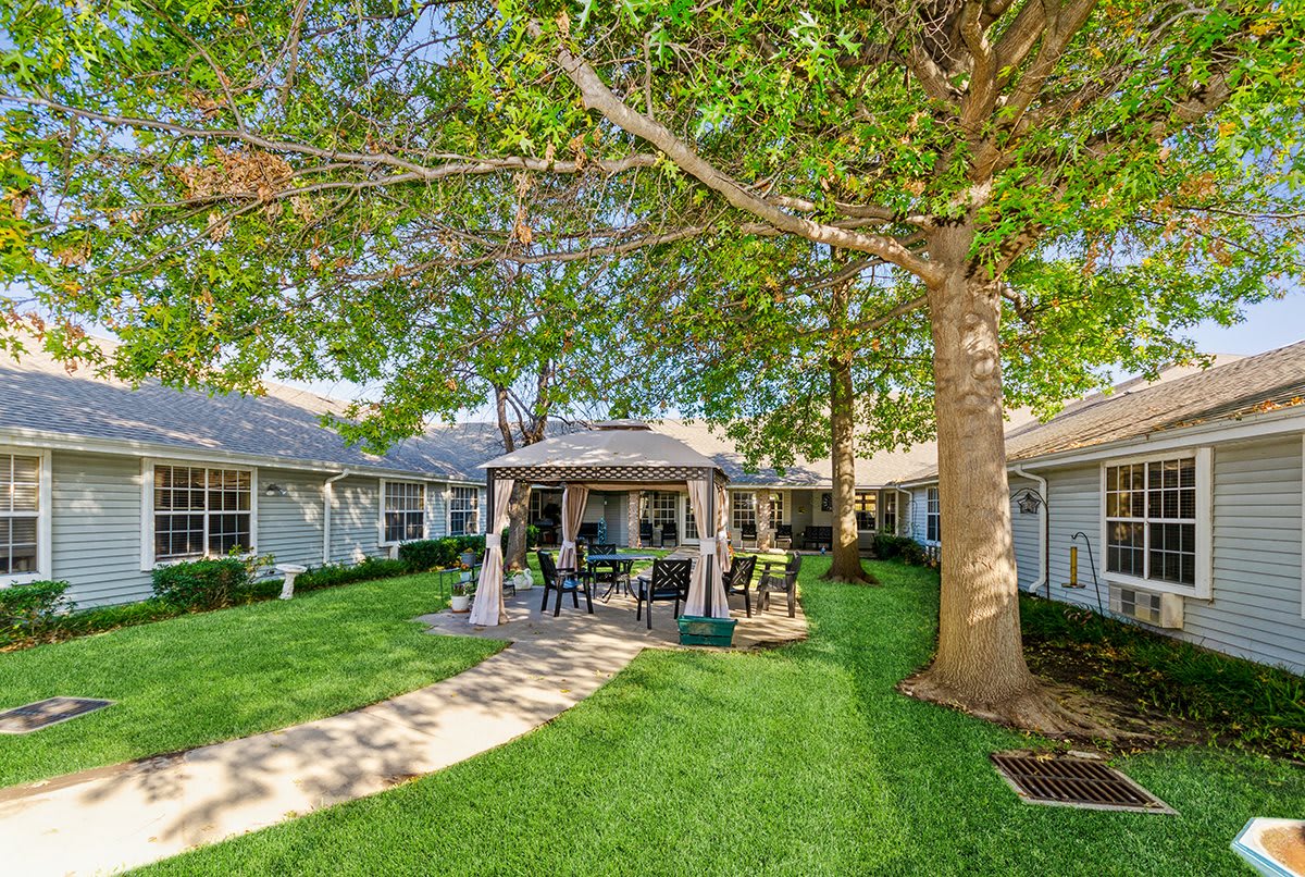 A serene backyard featuring a gazebo surrounded by lush greenery and outdoor seating.