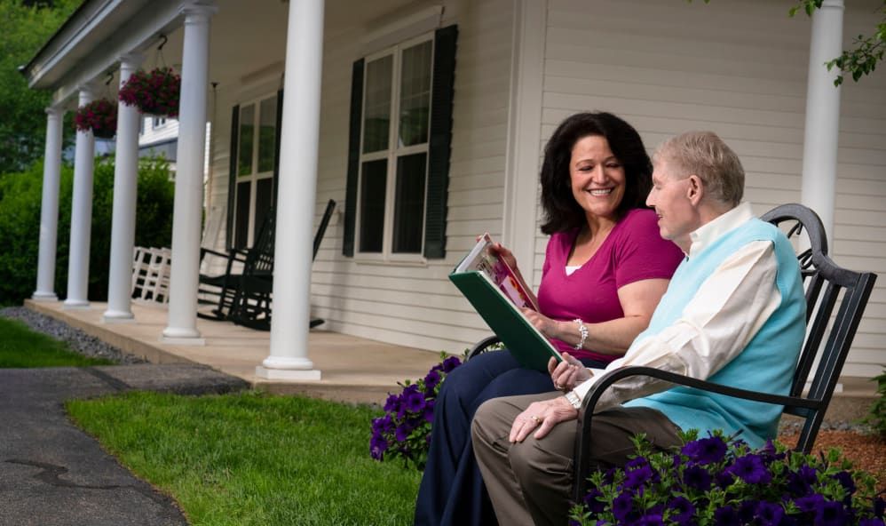 Two people sitting on a patio, enjoying a conversation while reading together.
