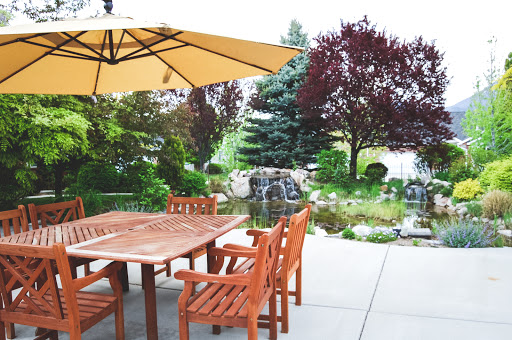 A serene outdoor patio area complete with wooden furniture, a sun umbrella, and a lush garden.