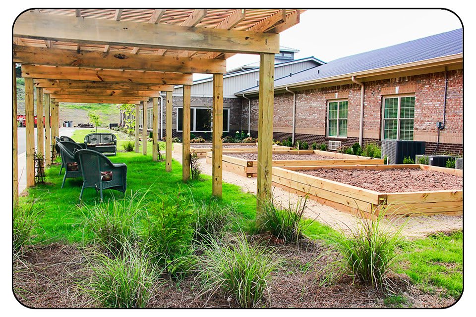 A landscaped garden area with a wooden pergola, benches, and raised beds.