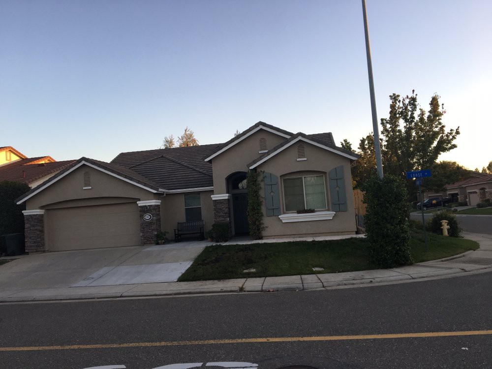 A suburban house with a well-maintained lawn and driveway, located on a quiet street.