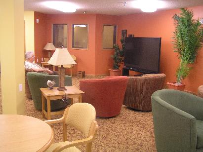 A cozy lounge area with colorful chairs, a large television, and soft lighting.