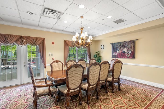 Elegant dining room with a chandelier, large wooden table, and upholstered chairs.