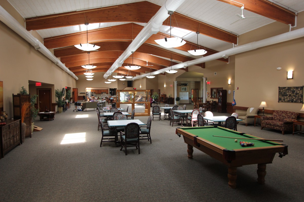 A spacious recreation room featuring a pool table and multiple seating areas.