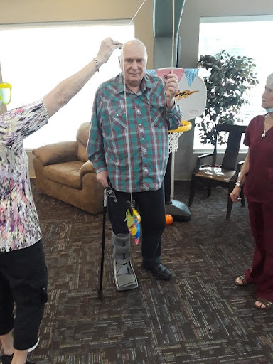 A joyful moment with an elderly man surrounded by caregivers, celebrating together in a cozy indoor environment.