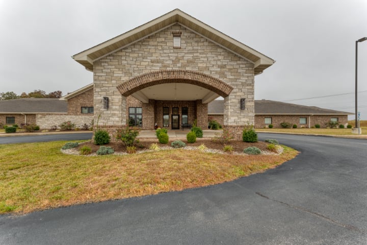 Front view of a building with a stone facade and landscaped entrance.
