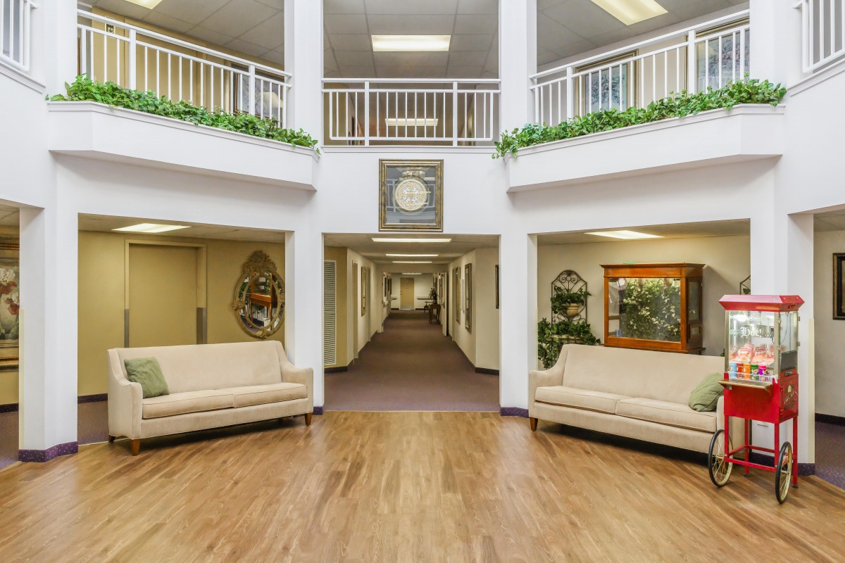 A spacious lobby with sofas, a clock, and decorative plants.