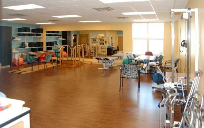 A spacious rehabilitation room equipped with various exercise and therapy equipment.