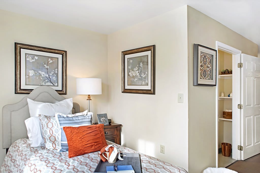 A cozy bedroom featuring stylish decor, with framed artwork on the walls and a bedside table with a lamp.