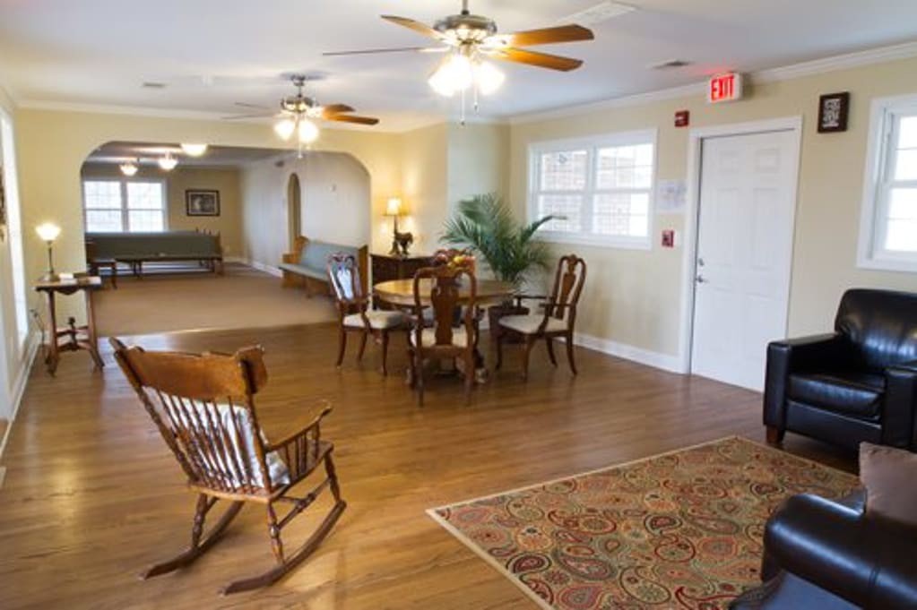 A cozy living space featuring a rocking chair, dining table, and ceiling fans.