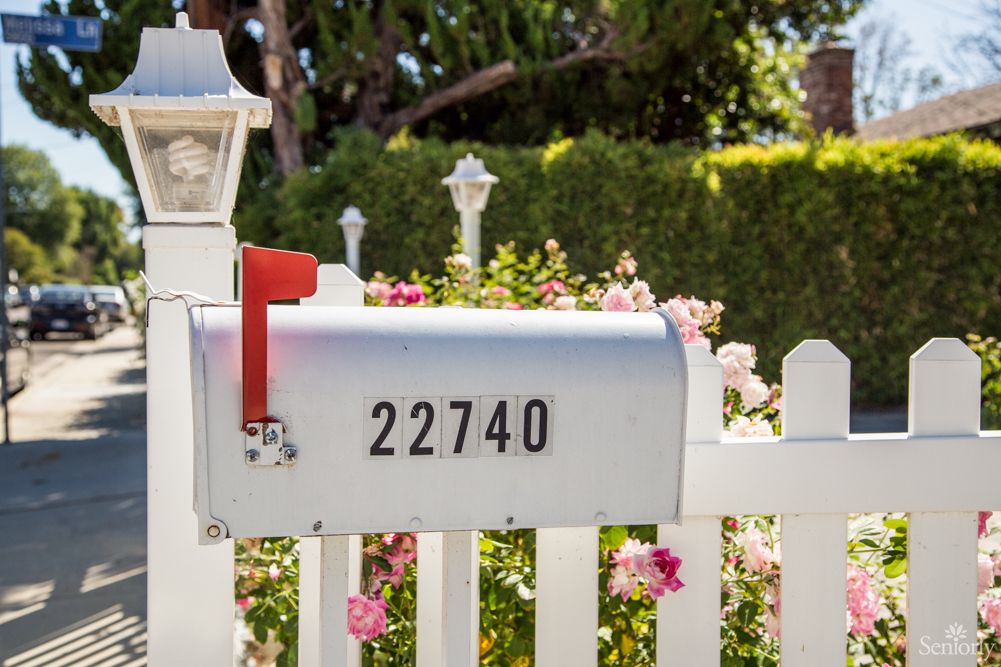 A white mailbox with the number 22740, set against a backdrop of flowers and a white picket fence.