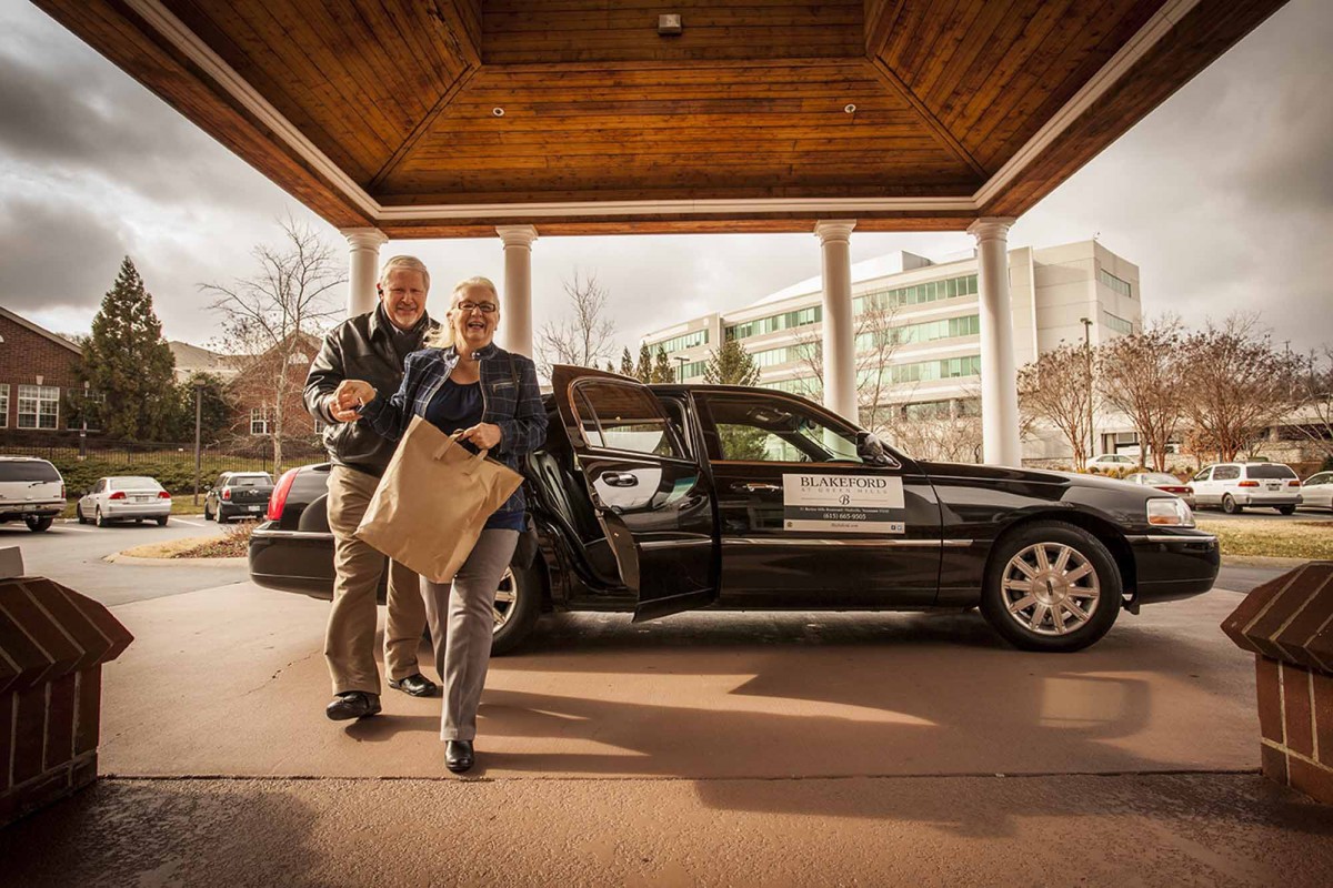 Business professionals arriving at a hotel in a limousine.