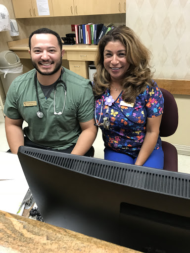 Two healthcare staff members smiling together at their desk in an office setting.