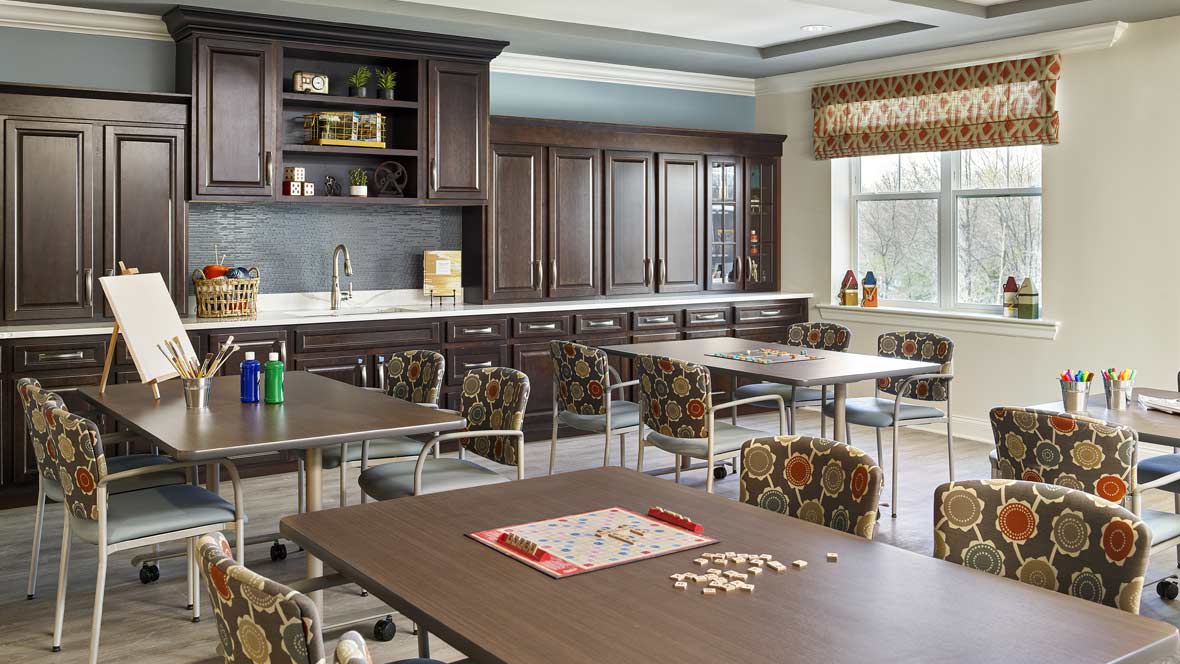 A well-organized kitchen and dining area featuring wooden cabinets, tables, and chairs with a game board setup.