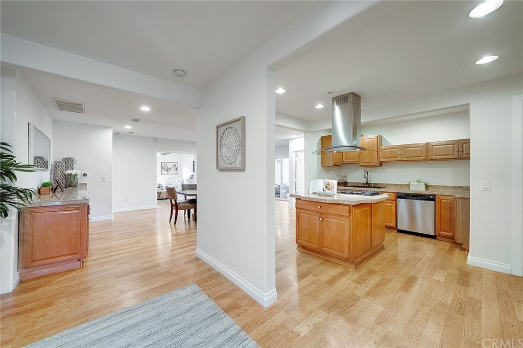 An open floor plan featuring a modern kitchen and dining area with hardwood floors and stainless steel appliances.