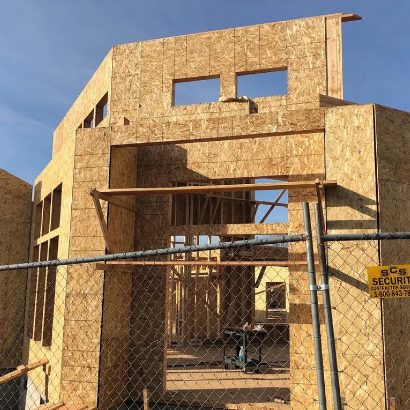 A wooden building structure under construction behind a fence.