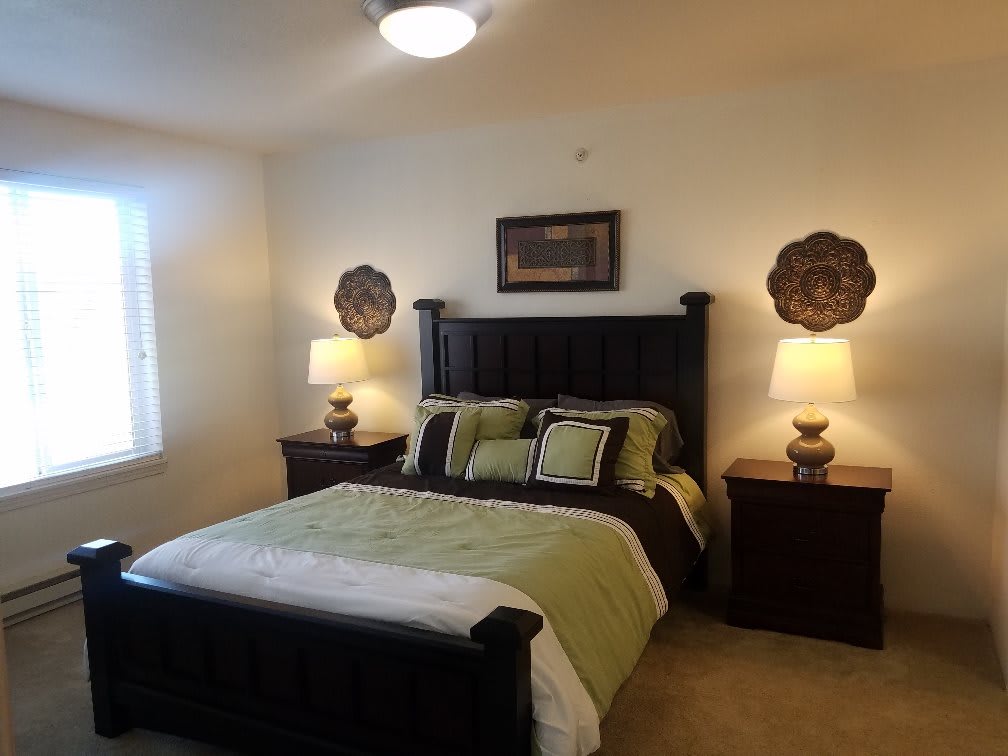 A cozy bedroom with a neatly made bed, two nightstands, and decorative lamps.