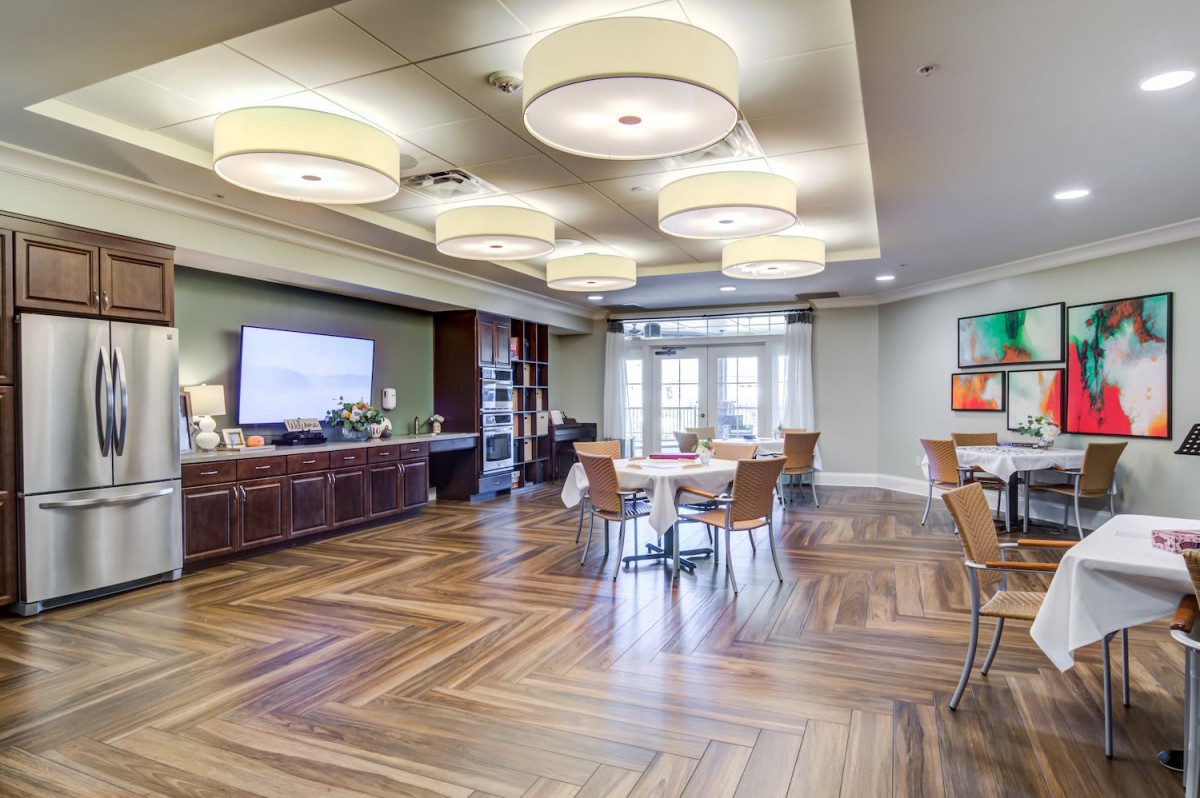 A modern conference room with elegant wood flooring, stylish ceiling lights, and a television screen ready for presentations.