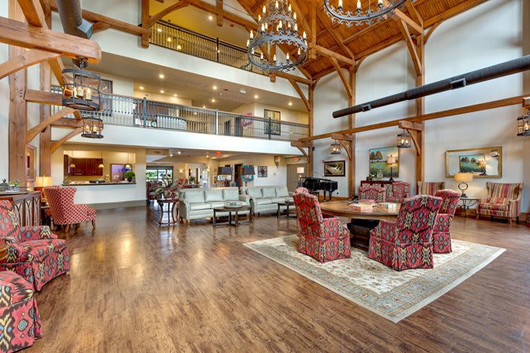 A spacious and elegantly designed living room with wooden beams and chandeliers.