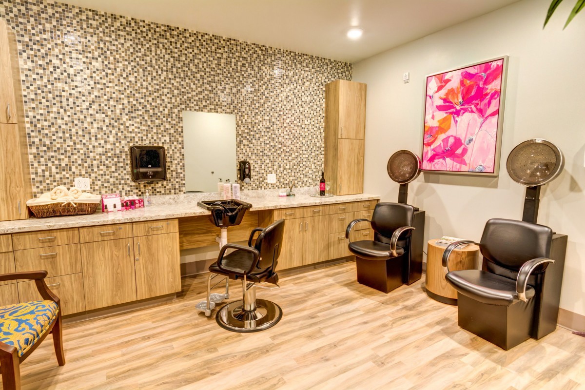 A modern hair salon featuring stylish chairs, a large mirror, and vibrant artwork on the wall.