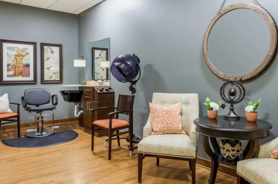 A cozy salon interior with styled chairs, a mirror, and hair drying equipment.